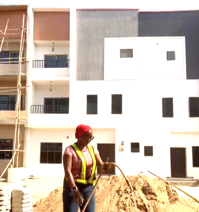 Saida on site in a hi-vis vest reviewing rolled construction drawings with a colleague